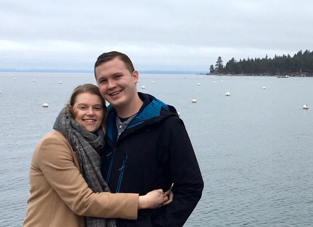 Mike and Lesley smiling together by a lake on an overcast day.